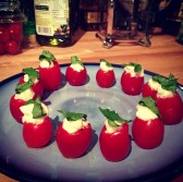 Cherry tomatoes stuffed with olive oil, mozzarella cheese, and topped with basil.